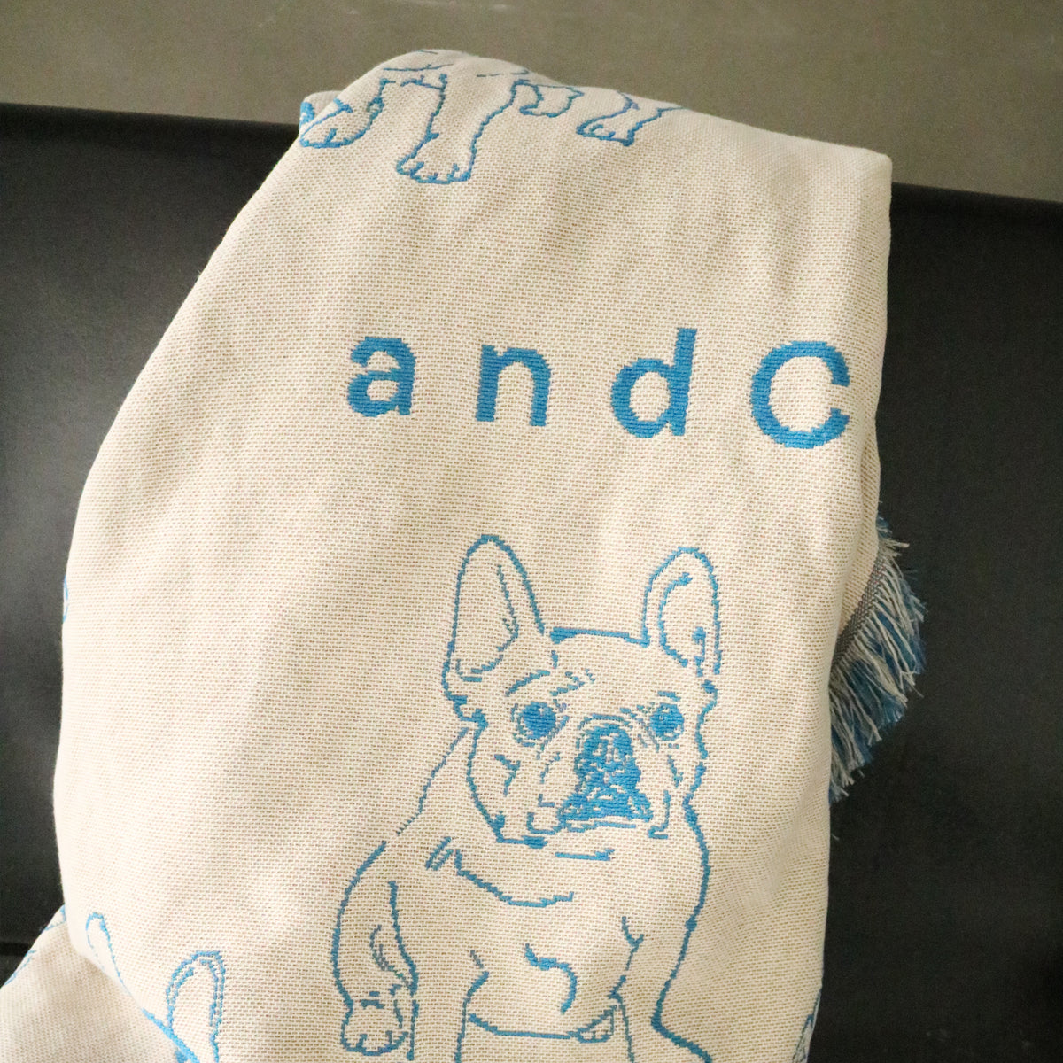 青い犬柄と文字を織り込んだandCharlieのブランケットの生地とフリンジ